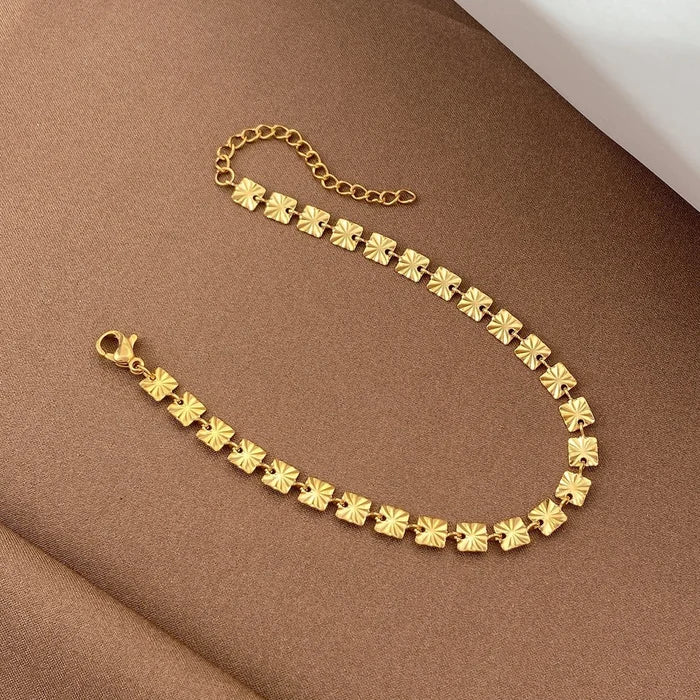 Gold-toned floral link bracelet on warm fabric